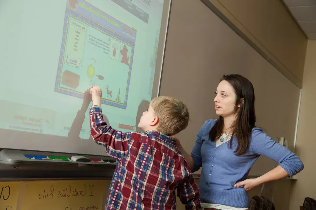 Student teacher working with student at smartboard